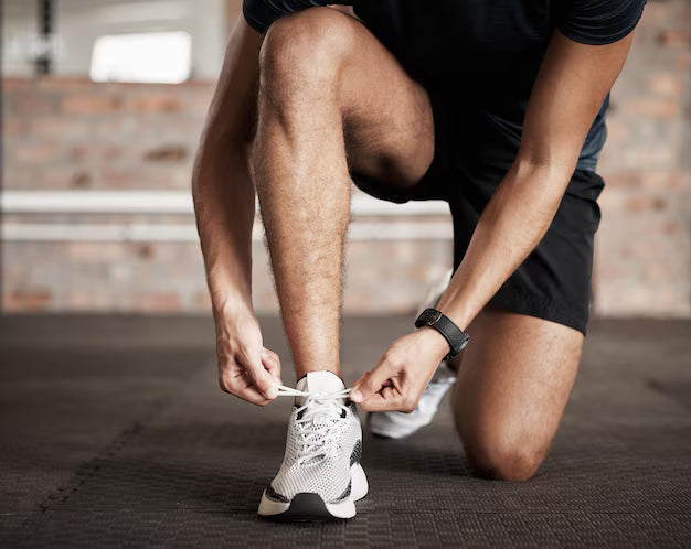 hombre arrodillado atandose zapatillas para entrenar