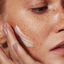 mujer de perfil hidratandose rostro aplicando crema